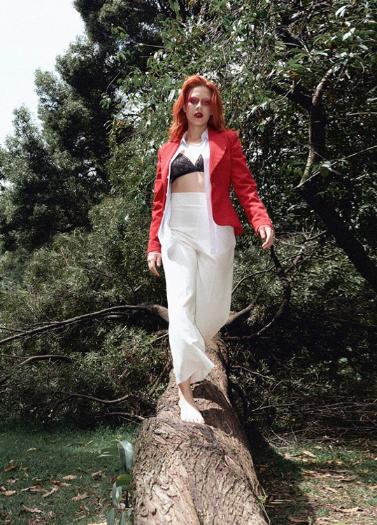 Fotografía editorial modelo caminando por un árbol caído.